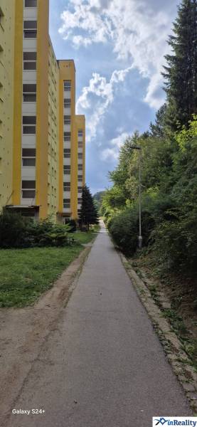 Žlutý bytový dům na Moskevské ulici v Banské Bystrici vedle chodníku a zeleně.