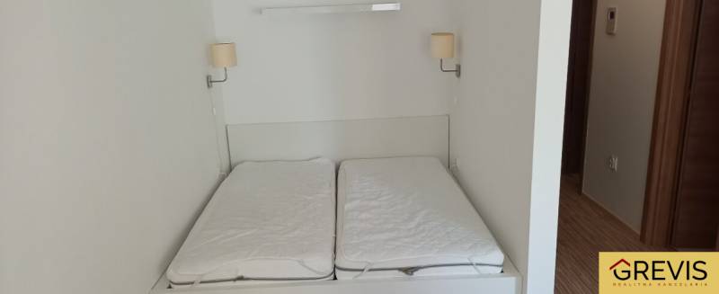 Manželská postel s lampami na stěně v 2-pokojovém bytě.