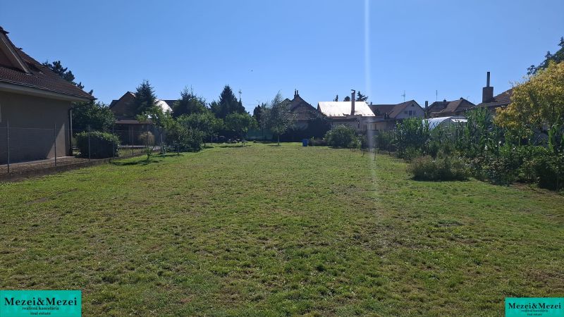 Pozemky na bydlení v Šelpiciach s travnatou plochou, obklopené domy a vegetací.