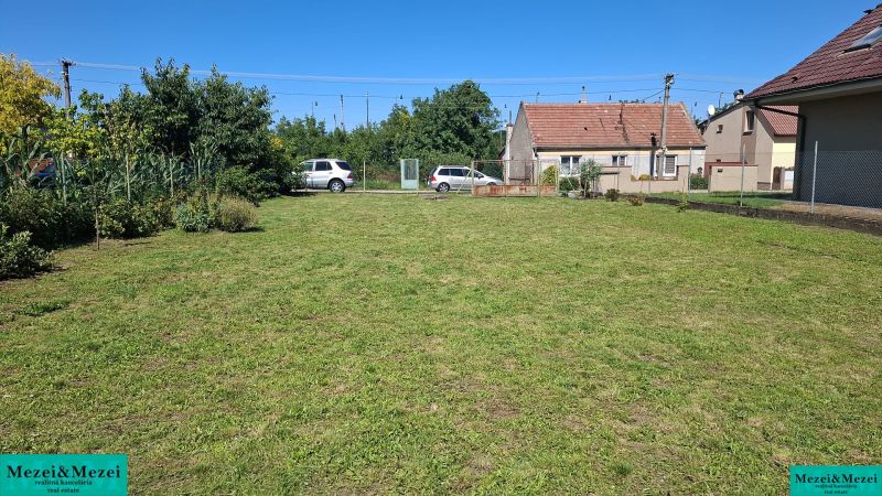 Travnatý pozemek na bydlení s domem a auty v Šelpiciach.