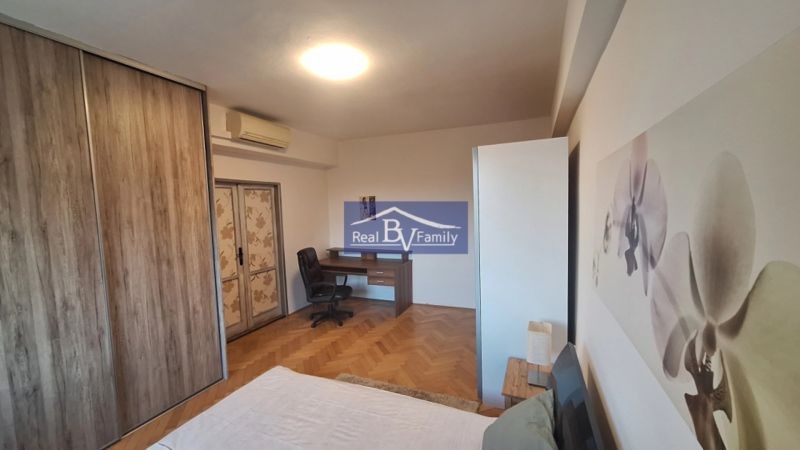 Ložnice s pracovním stolem, vestavěnou skříní a podlahou s dřevěným dekorem v 2pokojovém bytě.