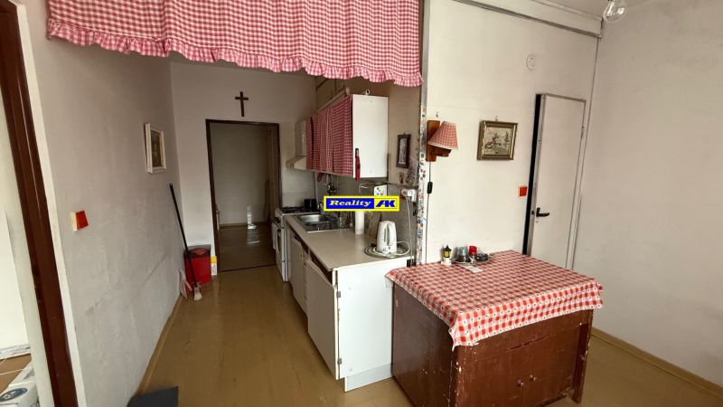 Kuchyně ve 3-pokojovém bytě s jednoduchým vybavením a dekorem v červené kostce.