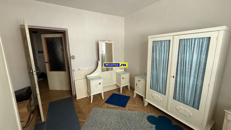 Pokoj s vintage nábytkem a podlahou s dřevěným dekorem v 3-pokojovém bytě.