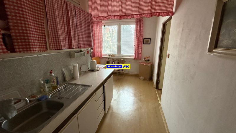 Kuchyně ve 3-pokojovém bytě se závěsy a podlahou s dřevěným dekorem.