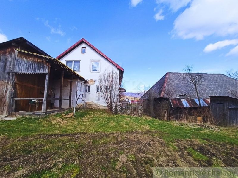 Rodinný dům v obci Zboj obklopený dřevěnými budovami a travnatým pozemkem.