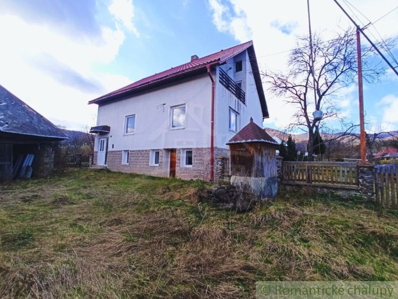 Rodinný dům ve Zboji s červenou střechou obklopený travnatým pozemkem a stromy.