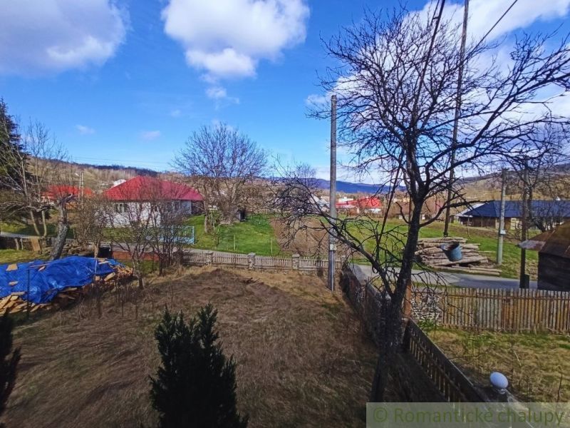 Pohled na zahradu rodinného domu s travnatou plochou a dřevinami.
