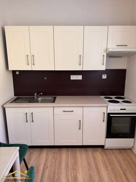 Kuchyňská linka v 1-pokojovém bytě s umyvadlem, sporákem a úložným prostorem.