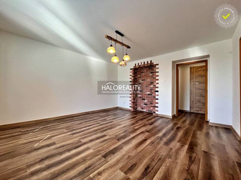 Obývací pokoj v 3-pokojovém bytě s podlahou s dřevěným dekorem a cihlovou stěnou.