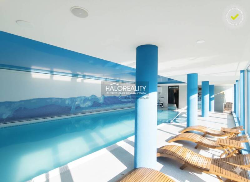 Interiérová relaxační zóna s bazénem a lehátky v gastro prostorech.