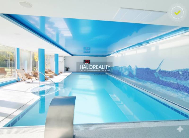 Bazén s modrými stropy a lehátky v interiérových gastro prostorech.