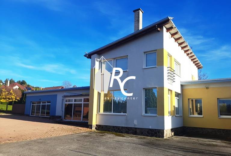 Rodinný dům v Necpalech, barevná fasáda, velký dvůr, slunečný jasný den.