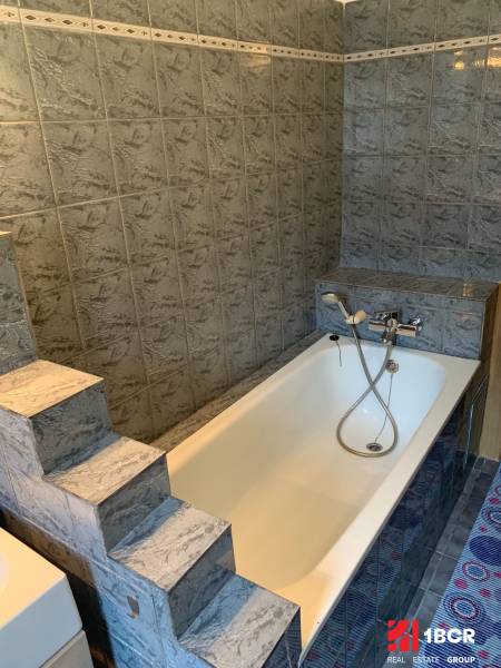 Koupelna s litinovou vanou a schůdky, typická pro 2-pokojový byt.