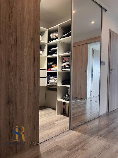 Vestavěná skříň s posuvnými dveřmi a podlaha s dřevěným dekorem v rodinném domě.