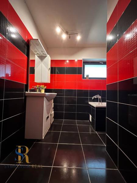 Černo-červená koupelna v rodinném domě se zrcadlem a vanou, výrazná kombinace obkladů.