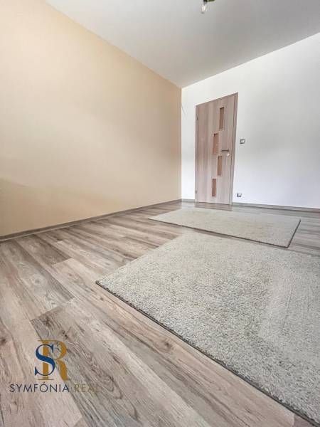 Pokoj v rodinném domě s podlahou s dřevěným dekorem a světlými stěnami.