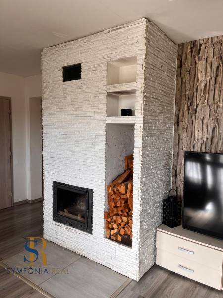 Interiér rodinného domu s krbem, TV a dřevem, podlaha s dřevěným dekorem.