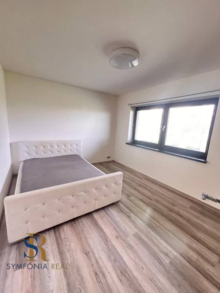 Ložnice v rodinném domě s postelí a podlahou s dřevěným dekorem.