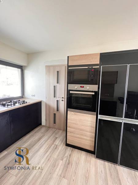 Kuchyně v rodinném domě s plynovým sporákem a spotřebiči, podlaha s dřevěným dekorem.