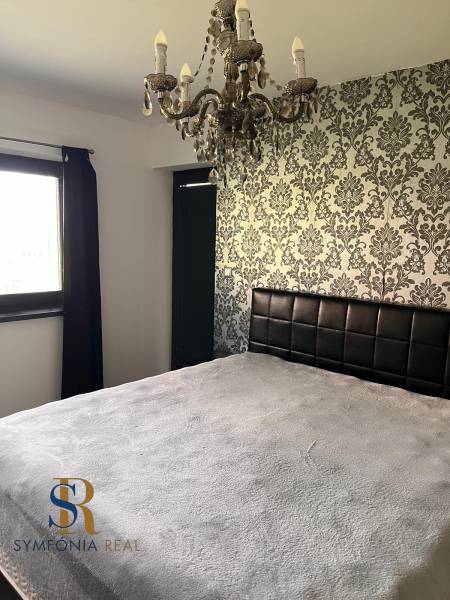 Ložnice v rodinném domě s dekorativní tapetou a lustrem. Symfonie interiérového designu.