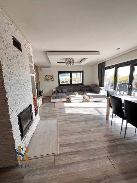 Interiér rodinného domu s pohovkou, krbem a podlahou s dřevěným dekorem.