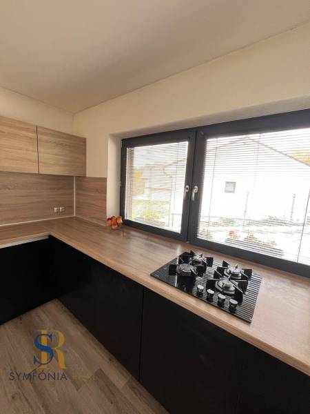 Kuchyně s dřevěným dekorem a pultem v rodinném domě, s oknem a plynovým vařičem.