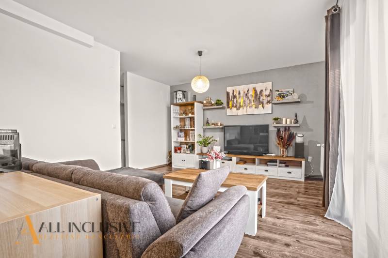 Obývací pokoj v 2-pokojovém bytě s podlahou s dřevěným dekorem, pohodlným sezením a dekoracemi.