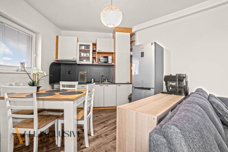 Kuchyně v 2pokojovém bytě s podlahou s dřevěným dekorem a jídelním stolem.