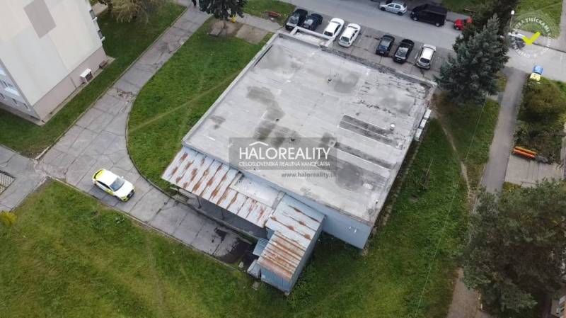 Budova obchodních prostor v Rimavské Sobotě s parkovištěm a přístupovou cestou.