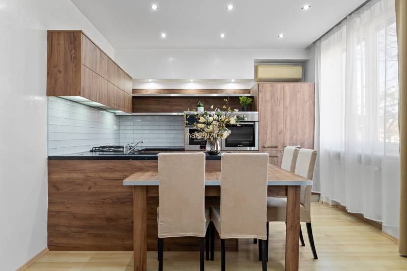 Kuchyně v 2-pokojovém bytě s dřevěným dekorem a světlým nábytkem.