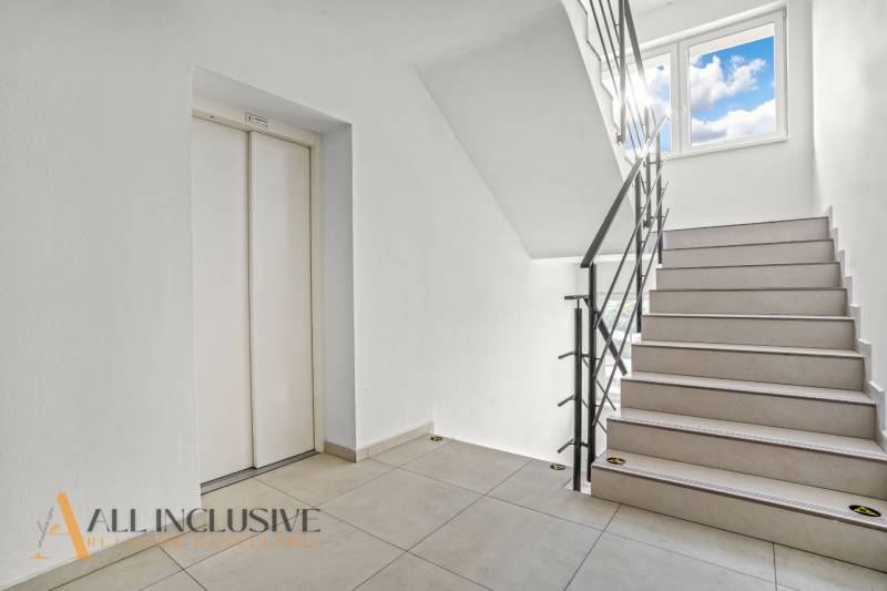 Schodiště se světlým obkladem a výtahem v 2-pokojovém bytě.