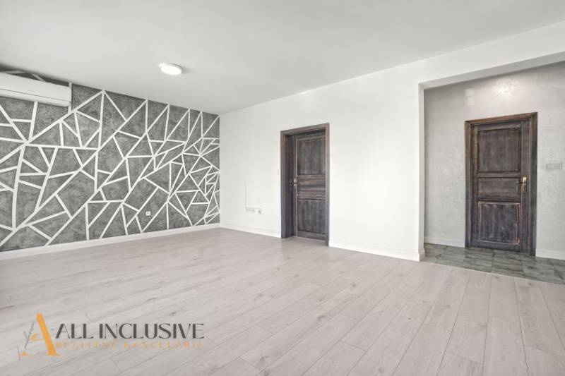 Obývací pokoj s podlahou s dřevěným dekorem a geometrickou stěnou v 2-pokojovém bytě.