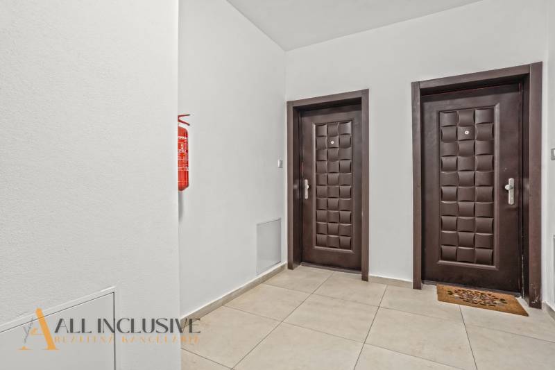 Chodba se dvěma dveřmi a hasicím přístrojem v 2-pokojovém bytě.