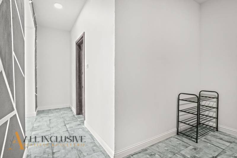 Chodba v 2-pokojovém bytě s podlahou s dřevěným dekorem a regálem na obuv.