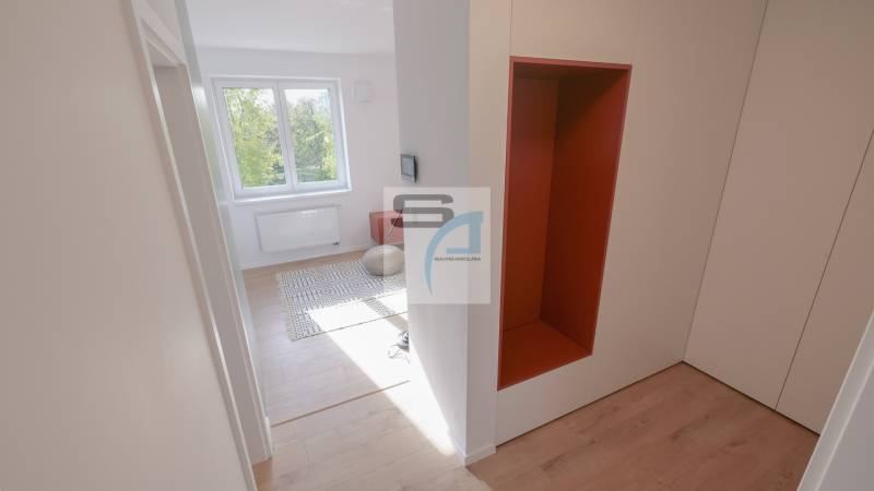 Chodba v 2-pokojovém bytě s podlahou s dřevěným dekorem a výhledem do místnosti.