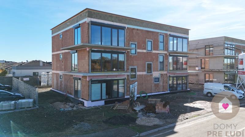 Novostavba na Duhové ulici ve Slovenském Grobu se zasklenými stěnami a parkovištěm.