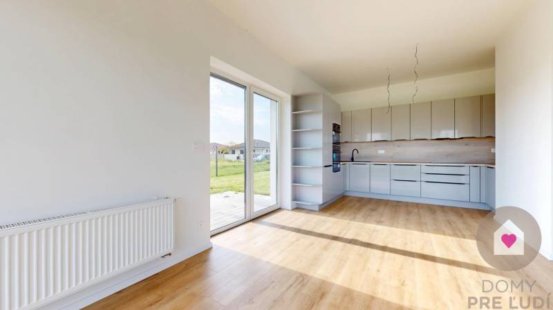 Kuchyně a obývací část ve 3pokojovém bytě s velkými okny a výhledem na zeleň.