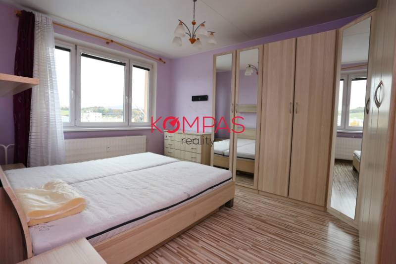 Světlá ložnice s podlahou s dřevěným dekorem v 3pokojovém bytě.