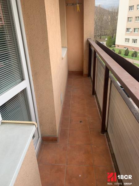 Balkon 2pokojového bytu s terakotovou dlažbou a výhledem na zeleň.