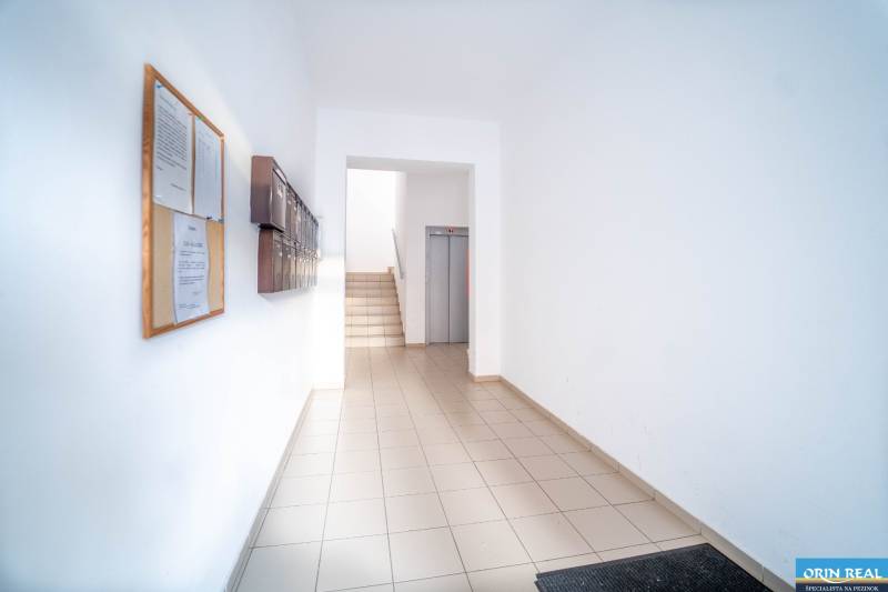 Bytový vchod s poštovními schránkami a výtahem, vhodný pro 2-pokojový byt.