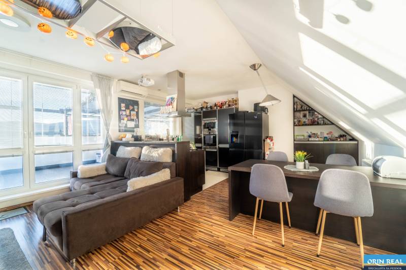 Obývací pokoj s kuchyní ve 2-pokojovém bytě s podlahou s dřevěným dekorem a pohodlnou sedačkou.