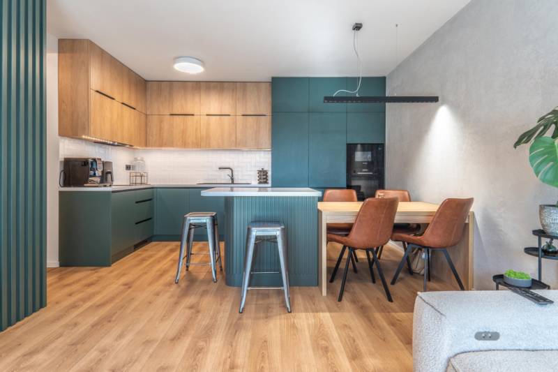 Kuchyně ve 3-pokojovém bytě s podlahou s dřevěným dekorem a jídelním stolem.