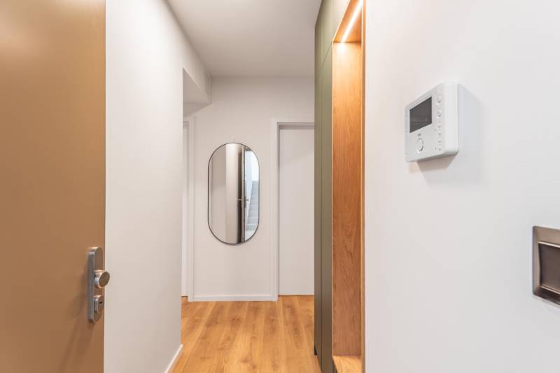 Na chodbě 3-pokojového bytu je zrcadlo a podlaha s dřevěným dekorem.