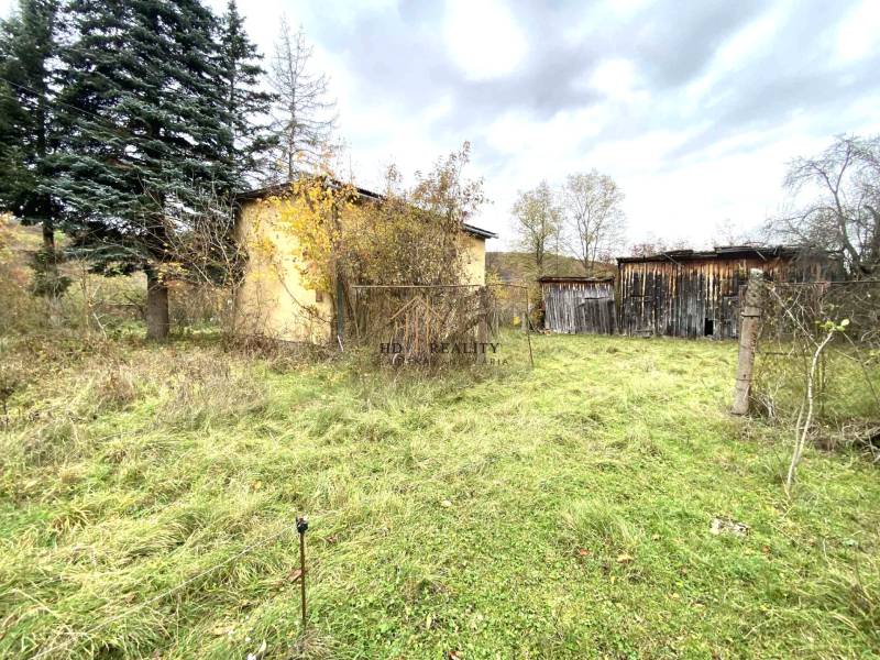 Rodinný dům v Rykynčicích, obklopený přírodou, vedle dřevěných konstrukcí a stromů.