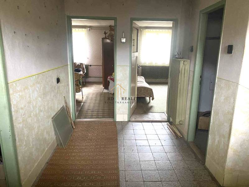 Interiér rodinného domu s chodbou a vstupem do pokojů, podlaha s dřevěným dekorem.