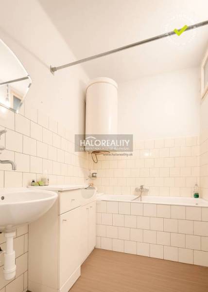 Koupelna v rodinném domě s vanou, umyvadlem a podlahou s dřevěným dekorem.