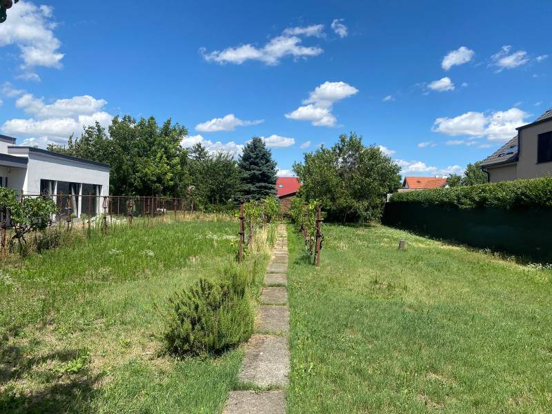 Pozemek pro bydlení na Nezvalově ulici v Bratislavě - Podunajské Biskupice obklopený zelení.