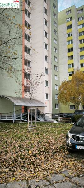 Panelový bytový dům na Korytnické ulici, Bratislava - Podunajské Biskupice, obklopený zelení.