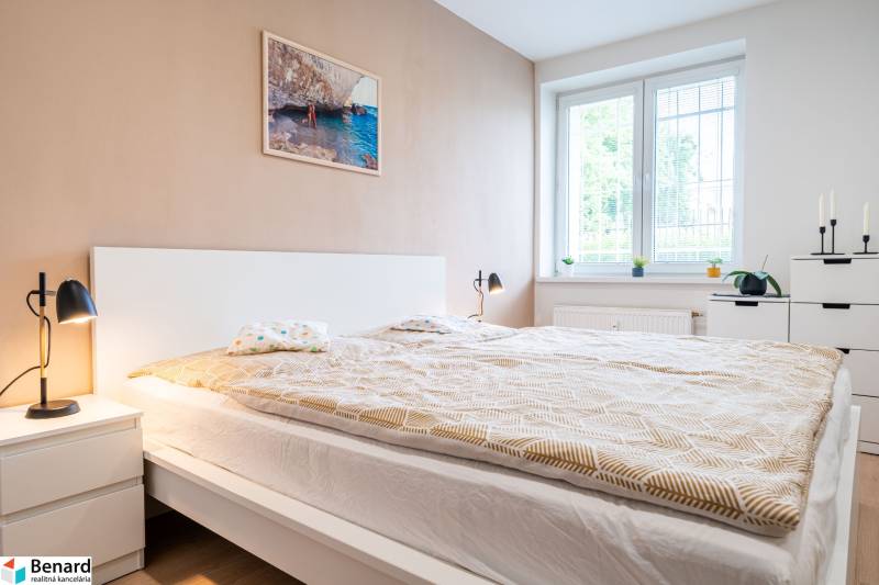 Ložnice v 3-pokojovém bytě s velkou postelí, stolními lampami a světlým interiérem.