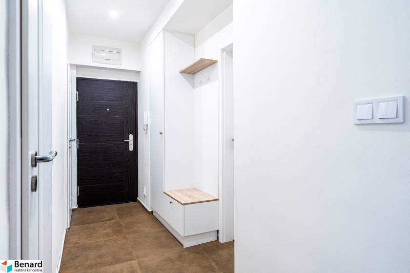 Světlá předsíň v 3-pokojovém bytě s hnědými dlaždicemi a úložným prostorem.